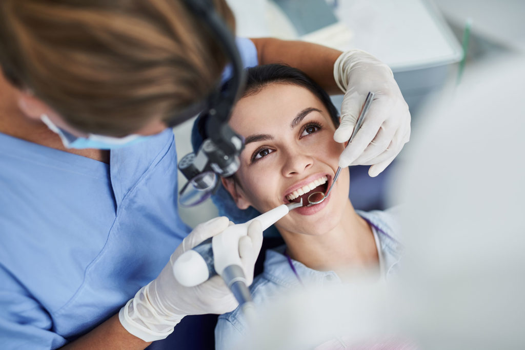 Une hygiéniste pratique un détartrage dentaire à une patiente.
