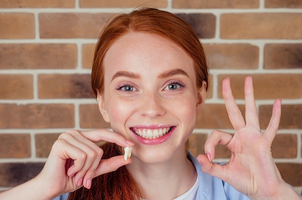 Jeune femme montre une dents de sagesse et sourit. après son traitement à notre cabinet dentaire à lausanne dentoffice